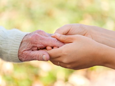 Senior and young holding hands outside
